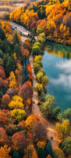 Herbst mit orangefarbenem Wald, türkisblauem See und Wanderwegen als Natur Hintergrundbild
