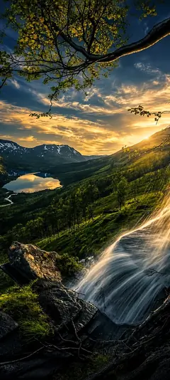 Majestätische Berglandschaft mit Wasserfall, grünem Tal, Bergsee und goldenem Sonnenuntergang als vertikales Handy Wallpaper