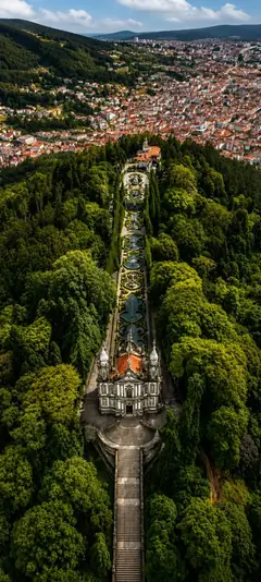 Bom Jesus do Monte in Braga Portugal mit barocker Treppe grünem Wald und Stadtblick als historisches Hintergrundbild