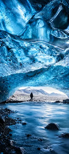 iPhone 18 Hintergrundbild mit blauer Eishöhle, Gletschersee, Eisformationen und verschneiten Bergen für iPhone 18 Pro und iPhone 18 Pro Max