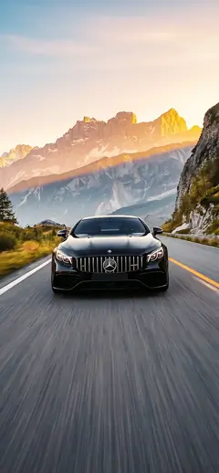 Mercedes AMG S63 Coupé schwarz Frontansicht auf Landstraße mit schneebedeckten Bergen und Sonnenuntergang Hintergrundbild