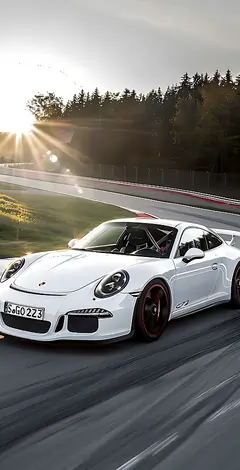 Weißer Porsche 911 GT3 fährt schnell auf einer Rennstrecke bei Sonnenuntergang
