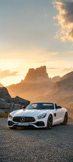Weißer Mercedes AMG Roadster auf einer Bergstraße bei Sonnenuntergang mit felsiger Landschaft als vertikales Handy Wallpaper