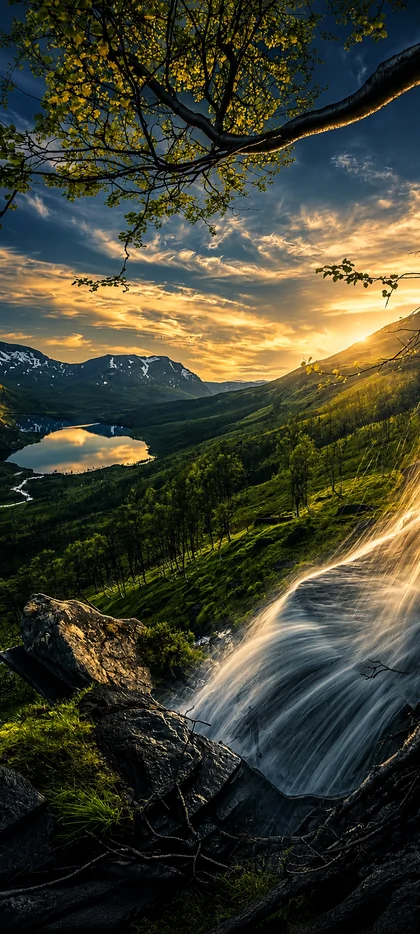 Majestätische Berglandschaft mit Wasserfall, grünem Tal, Bergsee und goldenem Sonnenuntergang als vertikales Handy Wallpaper