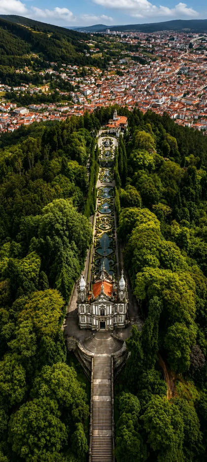 Bom Jesus do Monte in Braga Portugal mit barocker Treppe grünem Wald und Stadtblick als historisches Hintergrundbild