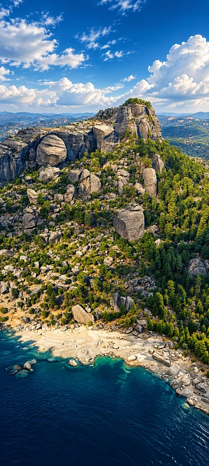 Felsige Küstenlandschaft mit türkisblauem Meer, bewaldeten Bergen und blauem Himmel als hochauflösendes Natur Hintergrundbild