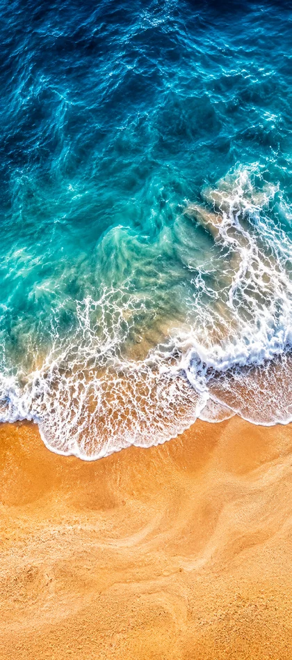 Sommer Strand Hintergrundbild mit türkisblauem Wasser, Meereswellen und goldenem Sand als Handy Wallpaper.