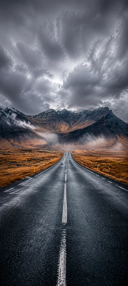 nasse straße durch dramatische berglandschaft unter dunklen wolken als straßen hintergrundbilder und schöne hintergrundbilder in 4k.