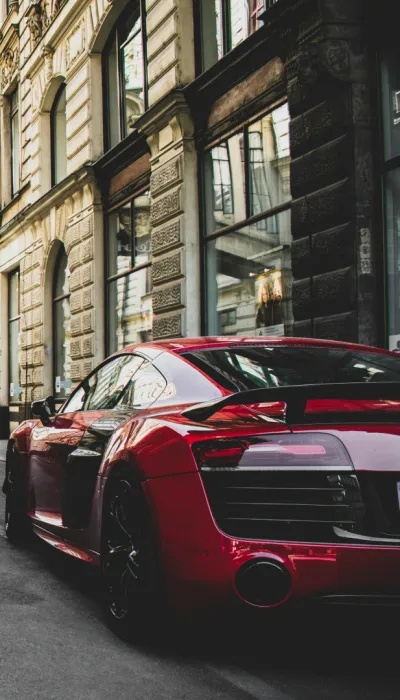 Rotes und schwarzes Audi R8 Coupé vor Betongebäude