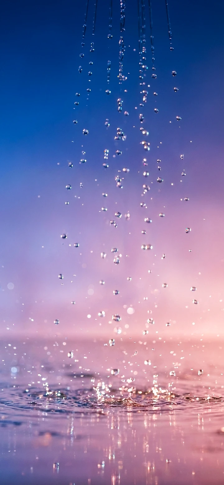 Vertikales Handy-Hintergrundbild: Makroaufnahme von fallenden Wassertropfen, die auf einer Wasseroberfläche aufprallen und Spritzer erzeugen, vor einem weichen Farbverlauf von Blau zu Lila.